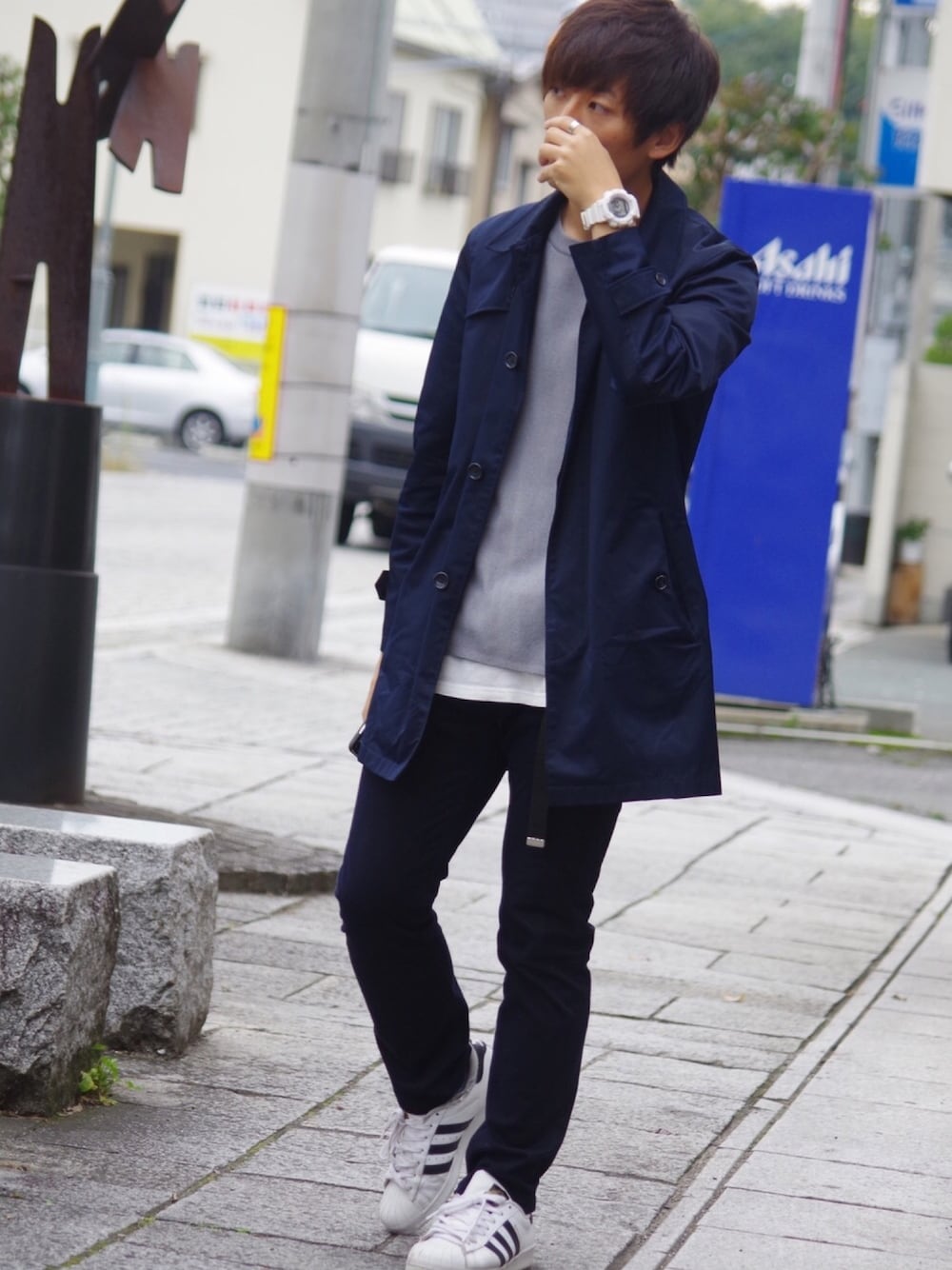 ブルー系のトレンチコート、グレー系のニット/セーター、ホワイト系のTシャツ/カットソーを着用したメンズの秋コーディネートの1枚目の写真