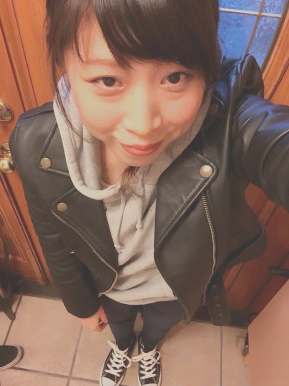 ブラック系のライダースジャケット、グレー系のパーカー、ブルー系のスラックスを着用したレディースの冬コーディネートの1枚目の写真