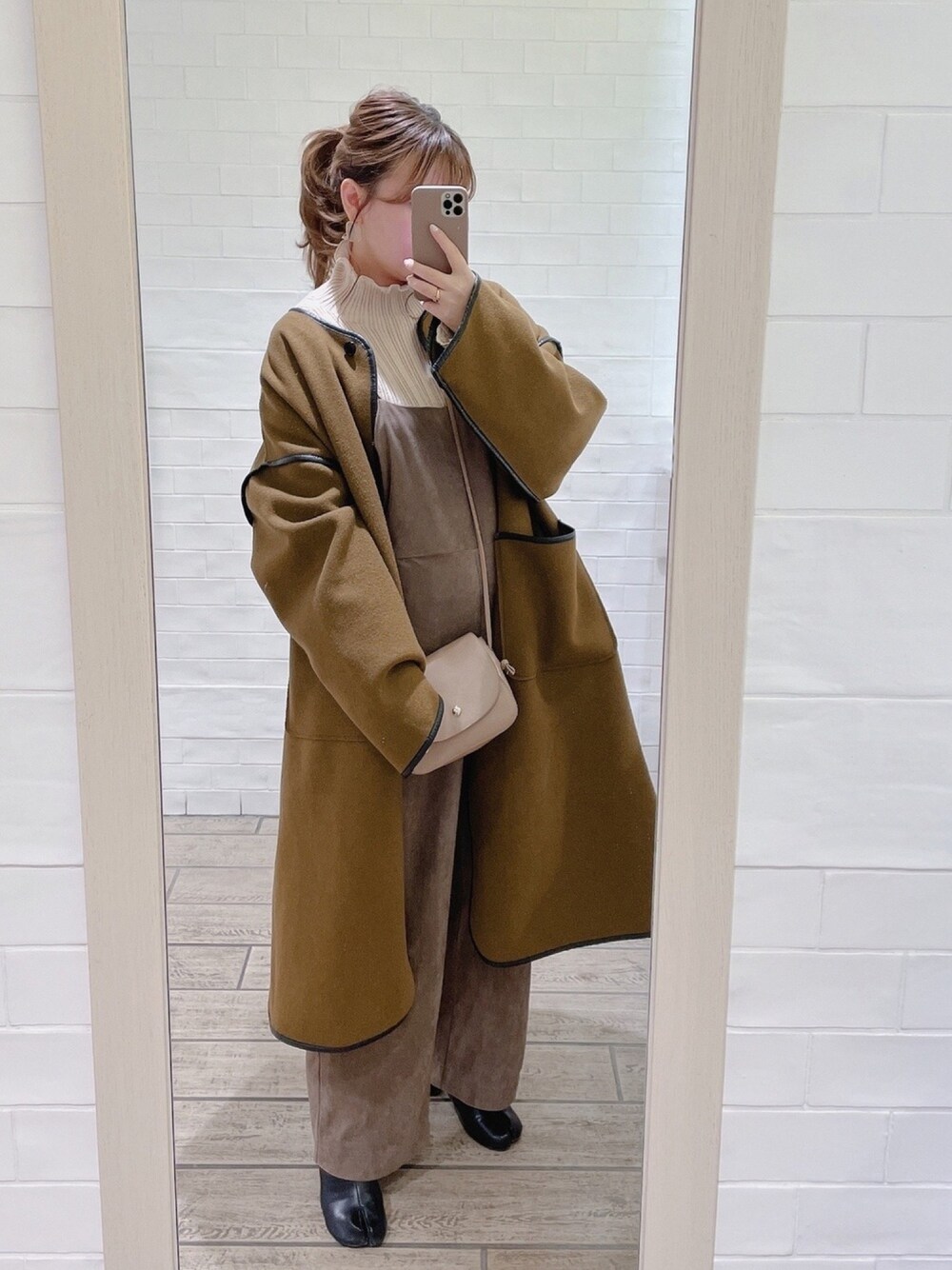 グリーン系のノーカラーコート、ホワイト系のニット/セーター、ベージュ系のショルダーバッグを着用したレディースの冬コーディネートの1枚目の写真