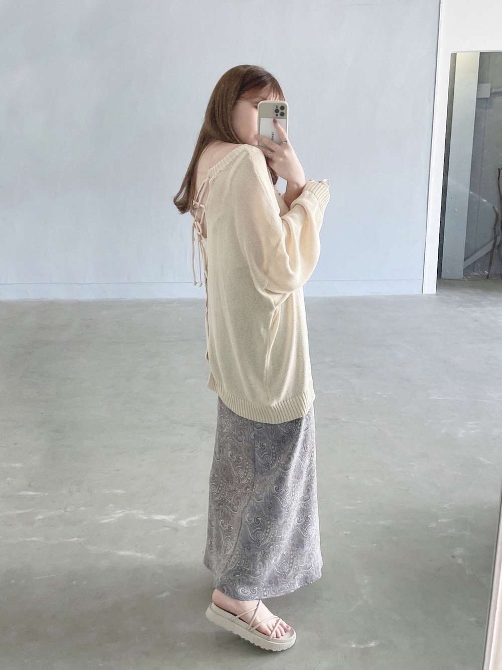 ホワイト系のニット/セーター、ブルー系のスカート、ベージュ系のサンダルを着用したレディースの春コーディネートの1枚目の写真