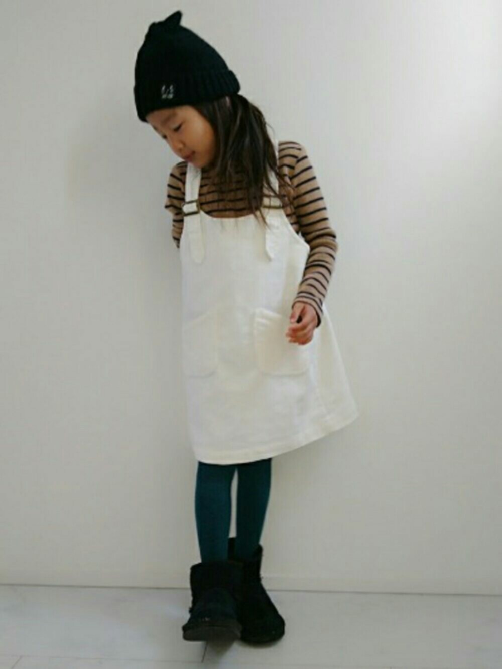 ホワイト系のジャンパースカート、イエロー系のTシャツ/カットソー、ブラック系のニットキャップ/ビーニーを着用したキッズの秋コーディネートの1枚目の写真