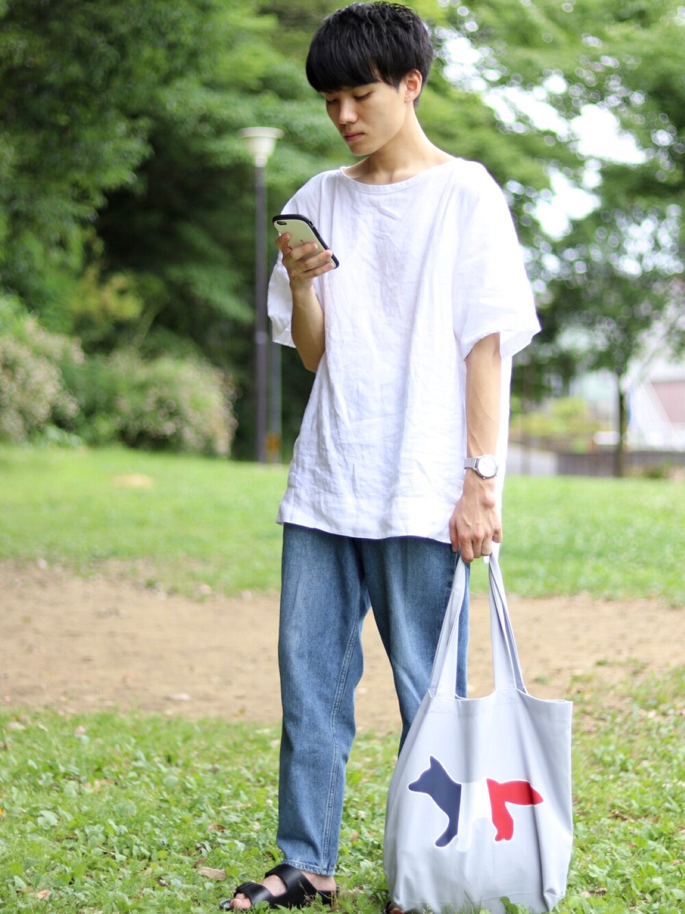 ホワイト系のTシャツ/カットソー、グレー系のトートバッグ、ブルー系のデニムパンツを着用したメンズの夏コーディネートの1枚目の写真