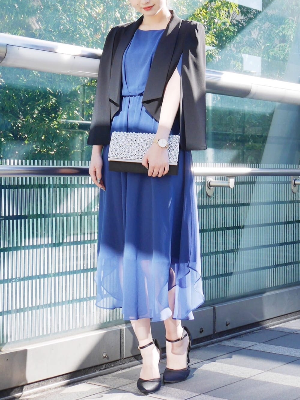 ブラック系のノーカラージャケット、ブルー系のドレス、ブラック系のクラッチバッグを着用したレディースの冬コーディネートの1枚目の写真