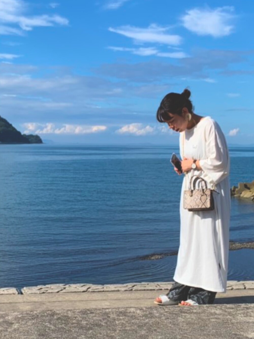 ホワイト系のワンピース、ブラック系のその他パンツ、ブラウン系のショルダーバッグを着用したレディースの秋コーディネートの1枚目の写真