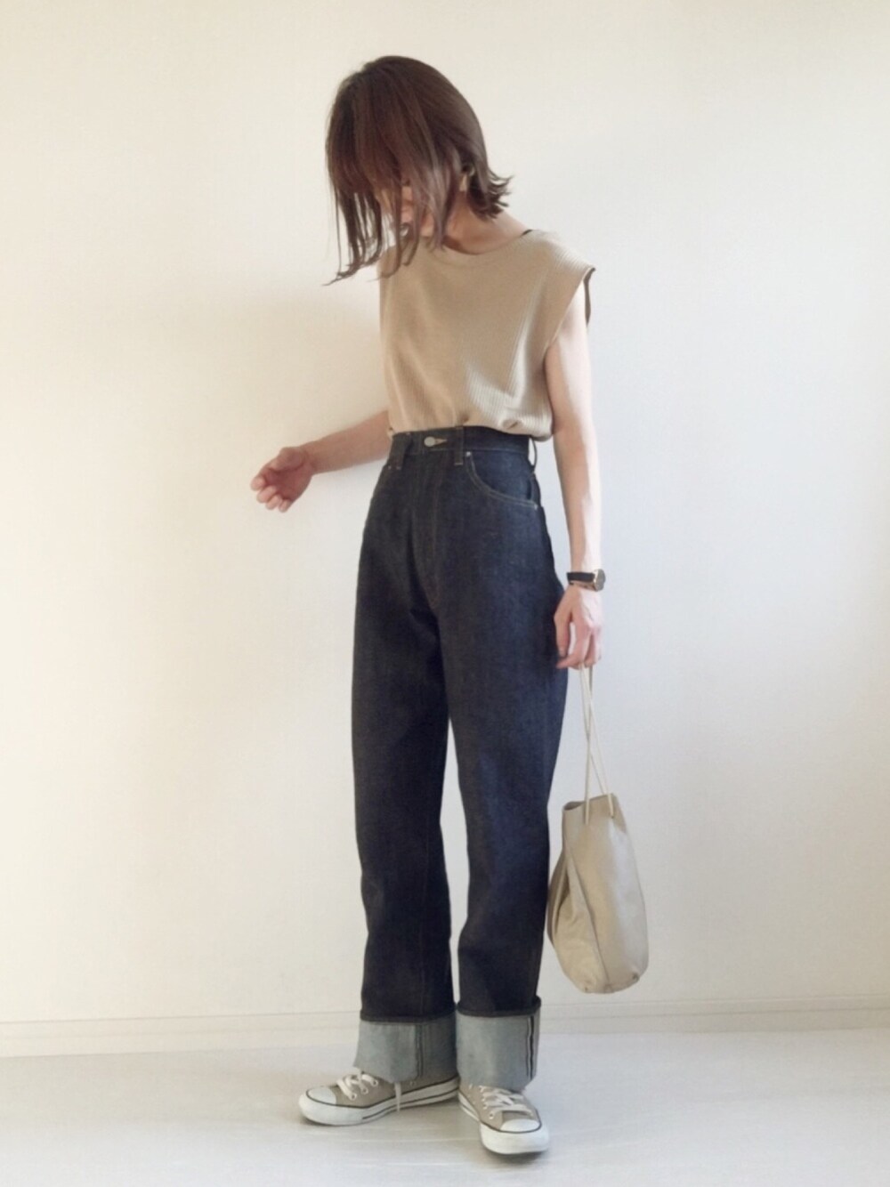 ベージュ系のTシャツ/カットソー、ブルー系のデニムパンツ、ベージュ系のショルダーバッグを着用したレディースの春コーディネートの1枚目の写真