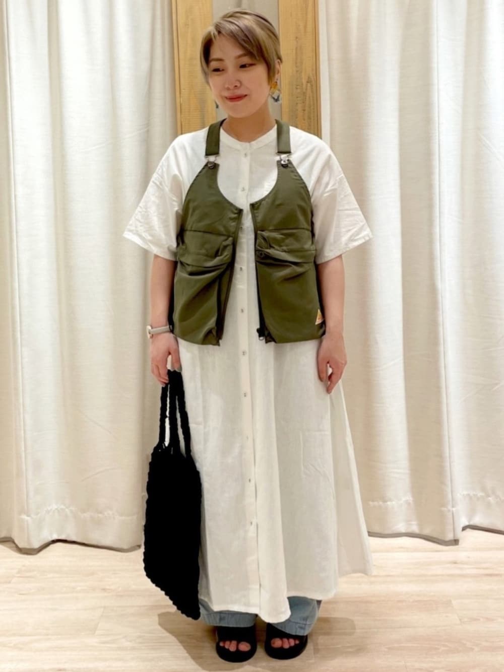グリーン系のベスト、ホワイト系のワンピース、ブラック系のトートバッグを着用したレディースの夏コーディネートの1枚目の写真