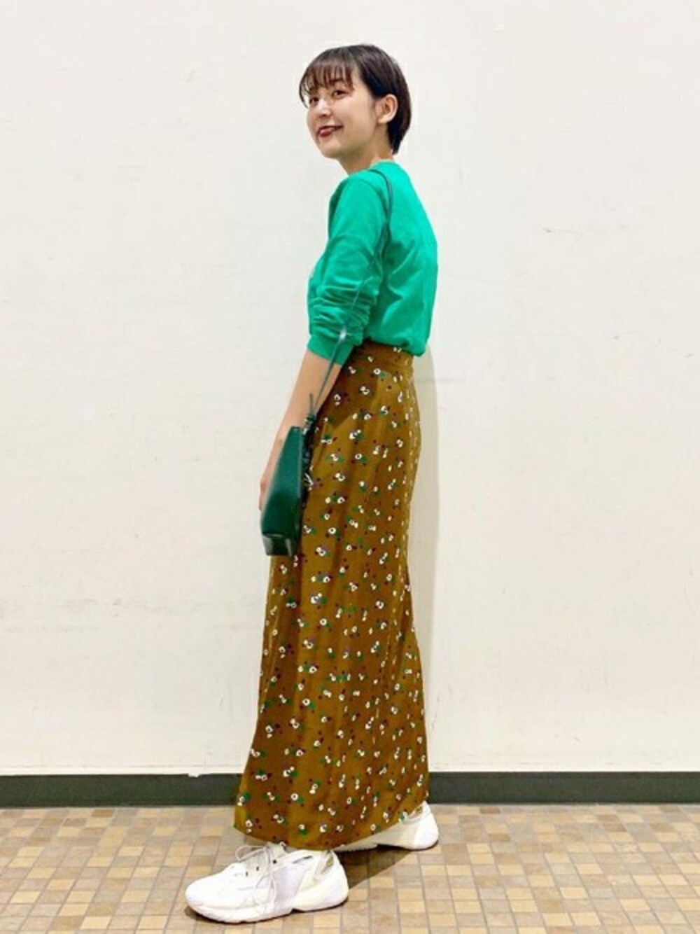 グリーン系のスカート、グリーン系のショルダーバッグを着用したレディースの秋コーディネートの1枚目の写真