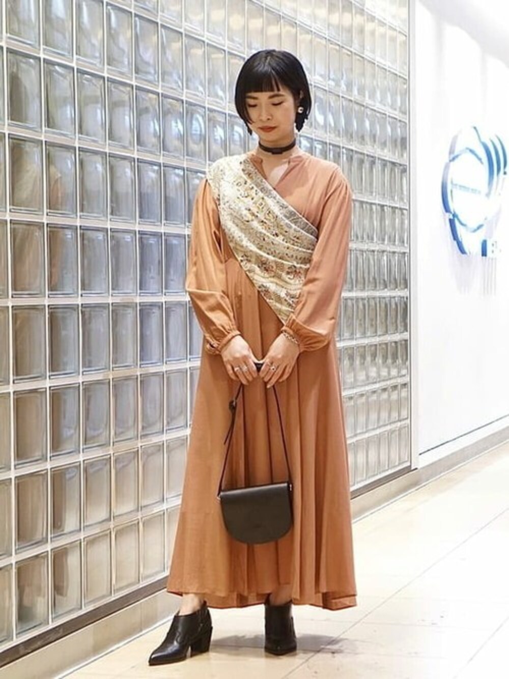 ブラウン系のワンピース、ブラック系のショルダーバッグ、ブラック系のブーツを着用したレディースの冬コーディネートの1枚目の写真