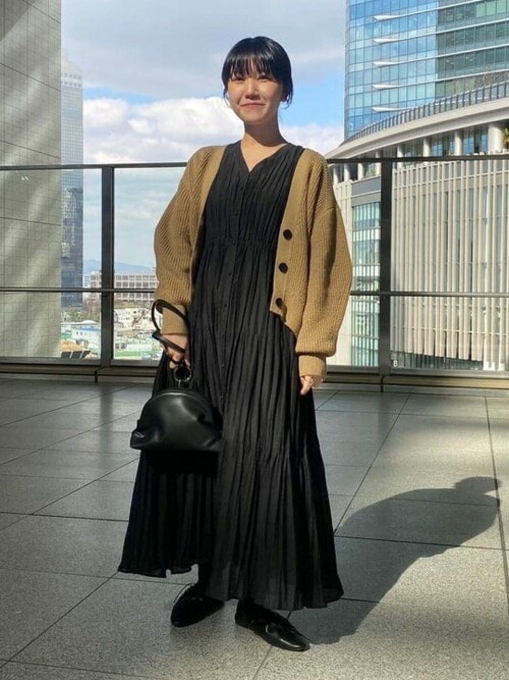 ベージュ系のカーディガン/ボレロ、ブラック系のワンピース、ブラック系のドレスシューズを着用したレディースの冬コーディネートの1枚目の写真