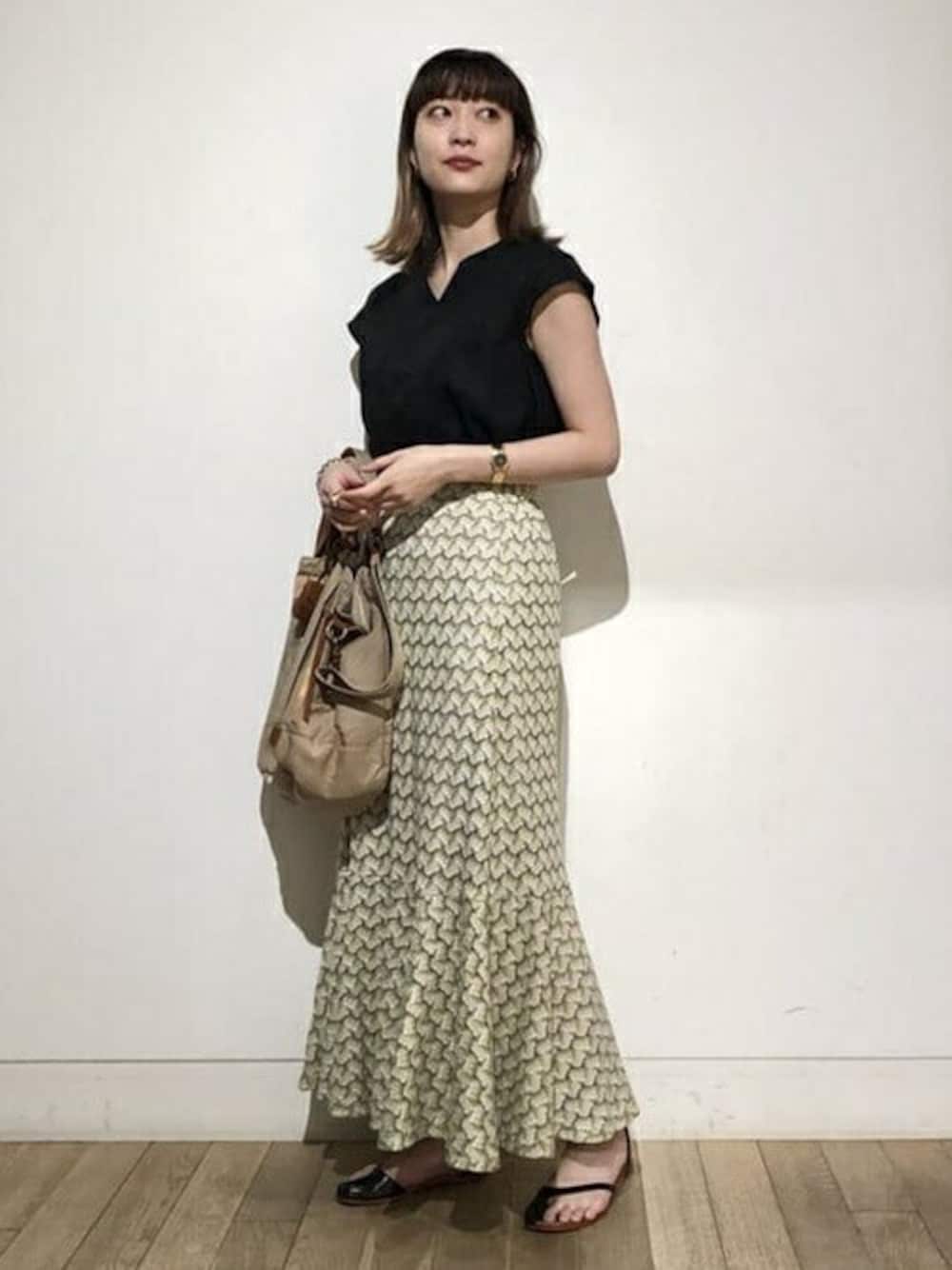 ブラック系のシャツ/ブラウス、グリーン系のスカート、ベージュ系のトートバッグを着用したレディースの夏コーディネートの1枚目の写真