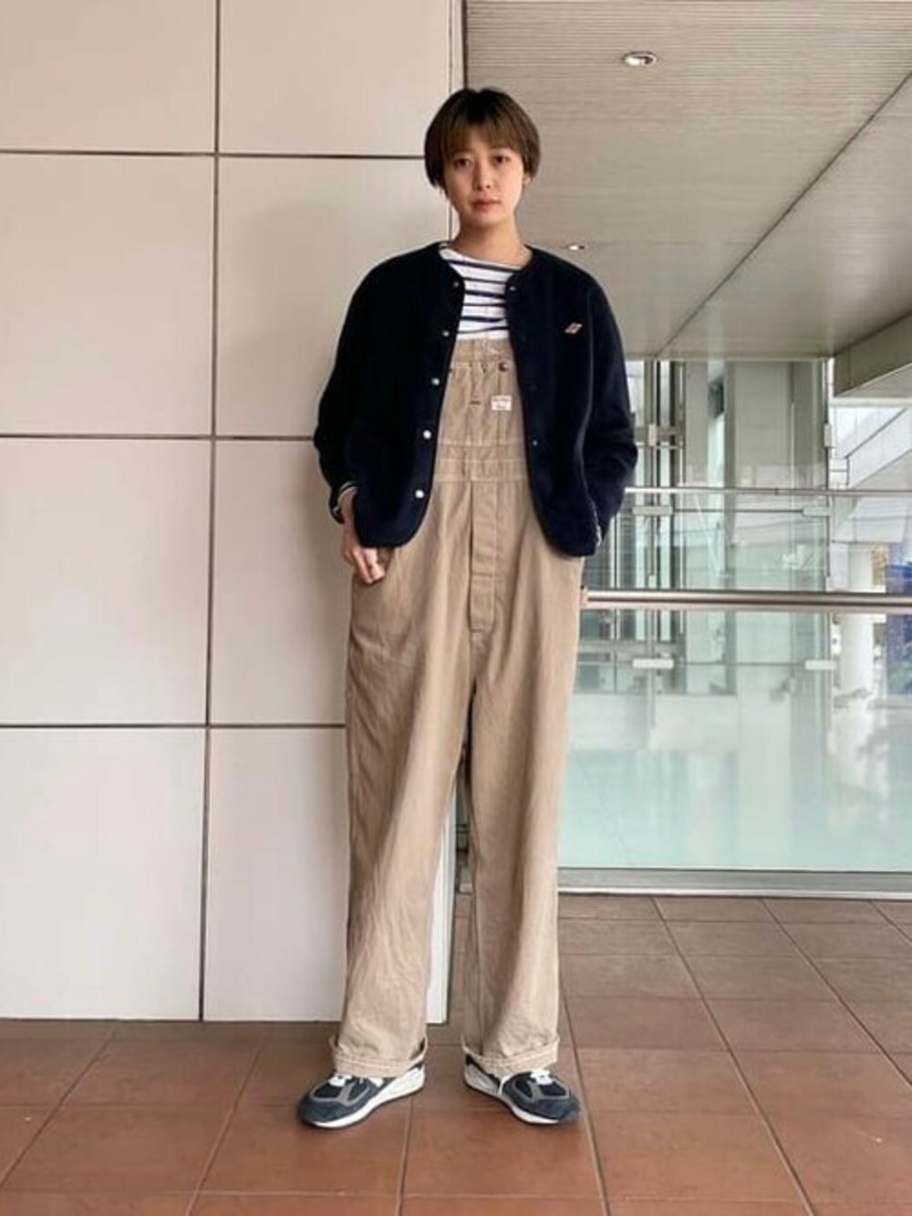 ブルー系のノーカラージャケット、ホワイト系のTシャツ/カットソー、ベージュ系のサロペット/オーバーオールを着用したレディースの秋コーディネートの1枚目の写真