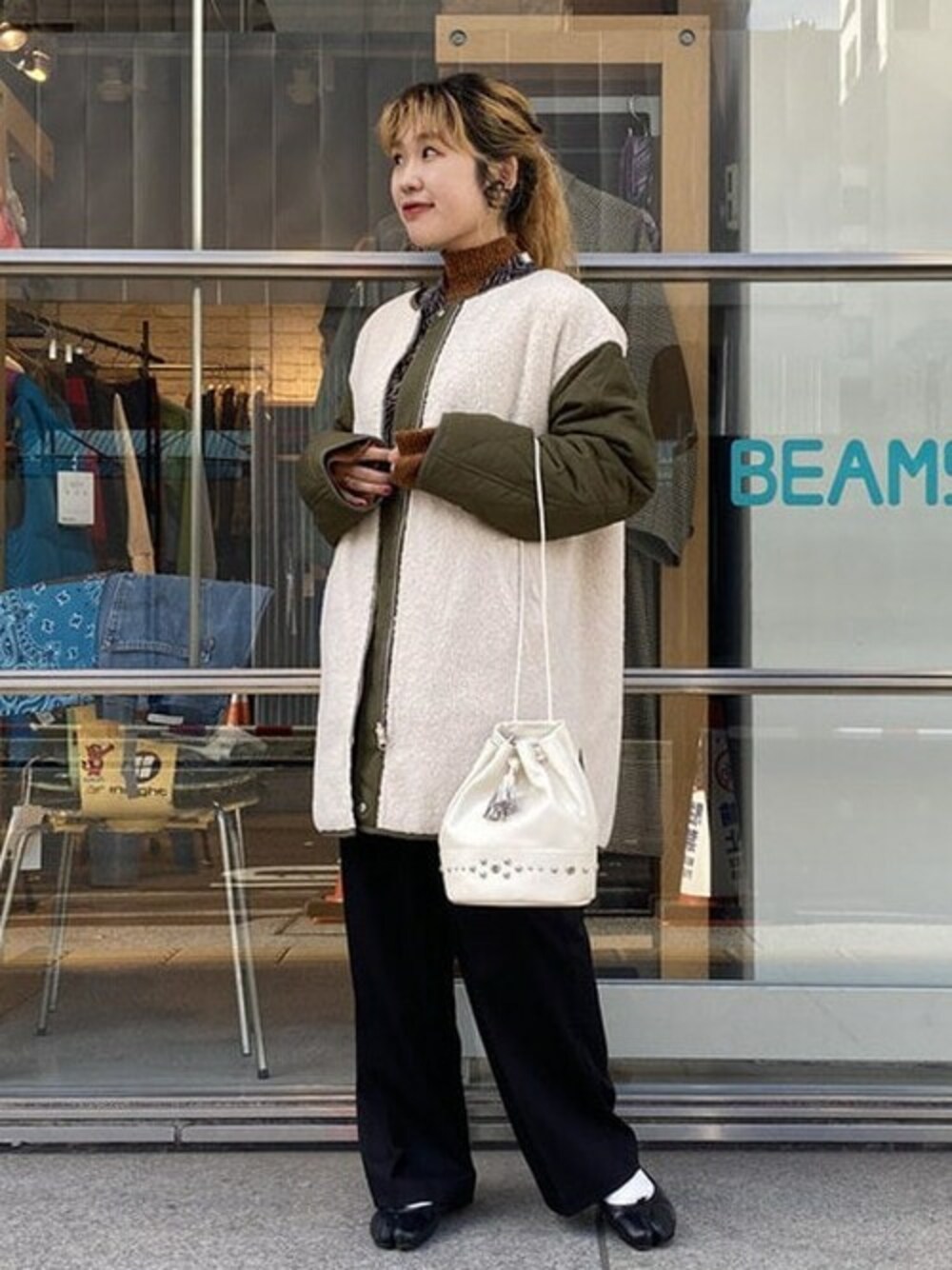 オレンジ系のニット/セーター、グリーン系のノーカラーコート、ホワイト系のショルダーバッグを着用したレディースの秋コーディネートの1枚目の写真