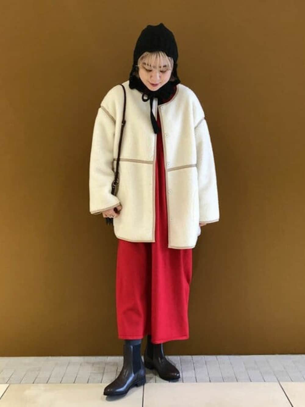 ホワイト系のノーカラージャケット、レッド系のワンピース、ブラウン系のブーツを着用したレディースの冬コーディネートの1枚目の写真