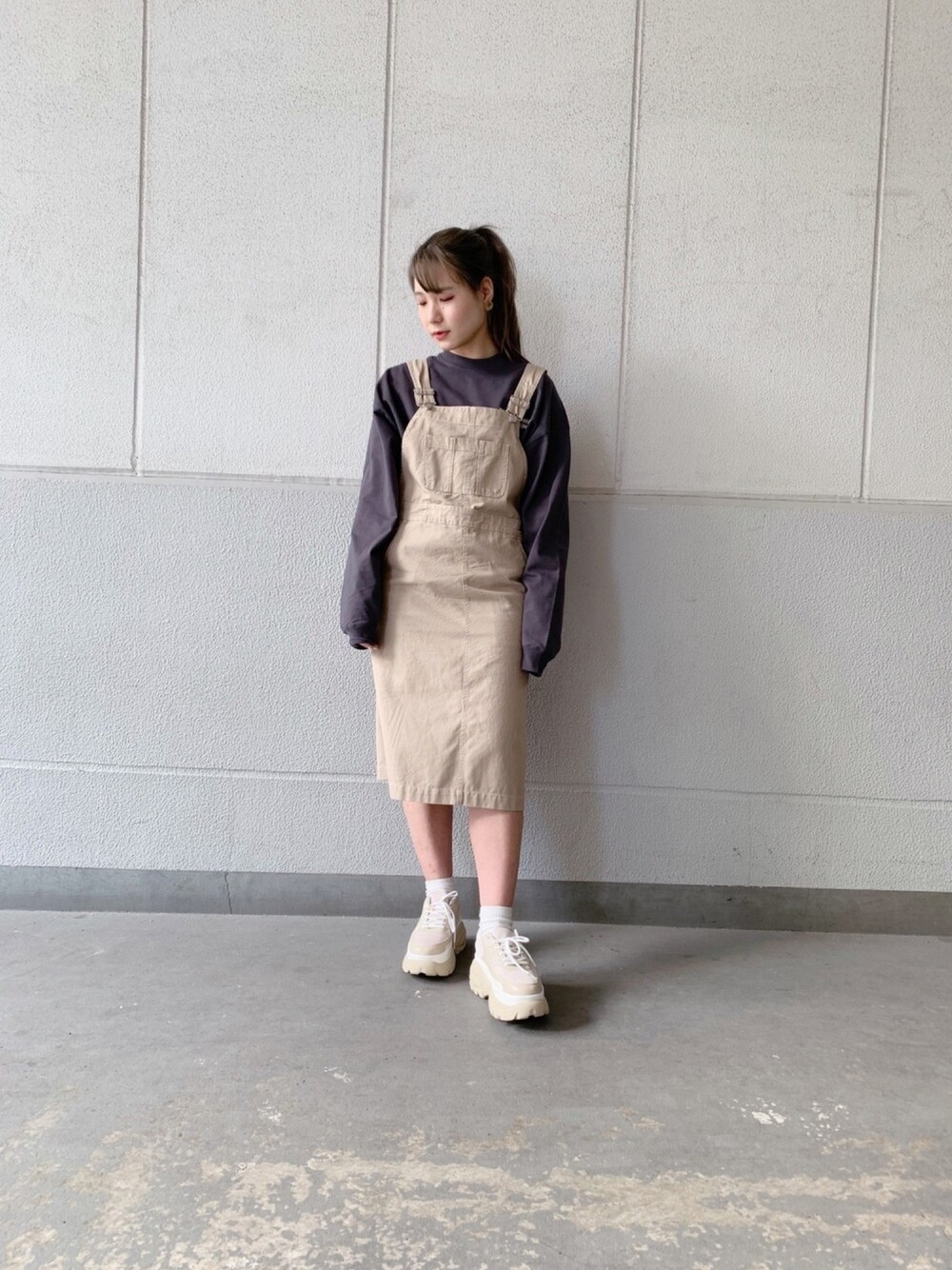 ブラック系のTシャツ/カットソー、ベージュ系のジャンパースカート、ベージュ系のスニーカーを着用したレディースの春コーディネートの1枚目の写真