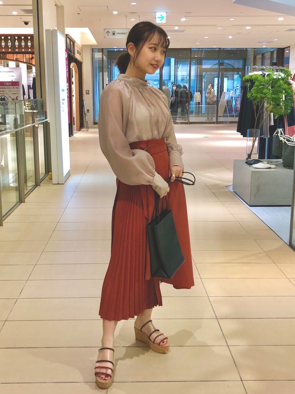 ベージュ系のシャツ/ブラウス、ブラック系のバッグ、オレンジ系のスカートを着用したレディースの春コーディネートの1枚目の写真