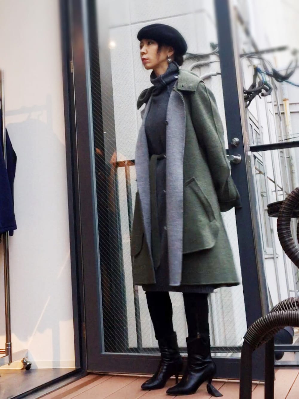 グレー系のトップス、ブラック系のブーツ、ブラック系のデニムパンツを着用したレディースの冬コーディネートの1枚目の写真