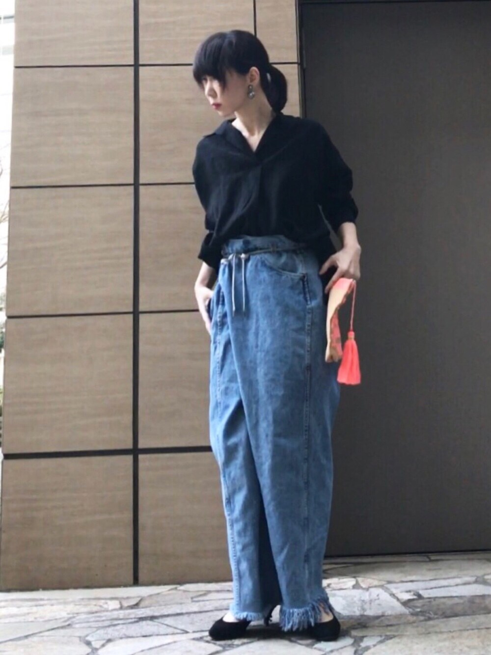 ブラック系のシャツ/ブラウス、ブルー系のデニムパンツ、オレンジ系のクラッチバッグを着用したレディースの春コーディネートの1枚目の写真