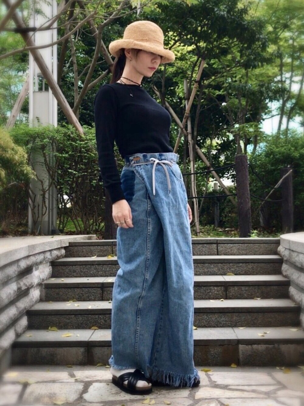 ブラック系のTシャツ/カットソー、ブルー系のデニムパンツ、ブラック系のサンダルを着用したレディースの春コーディネートの1枚目の写真