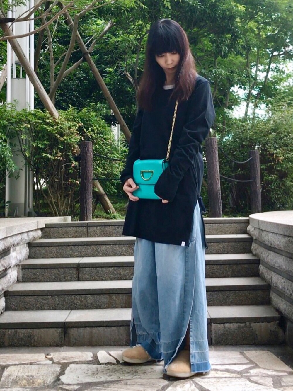 ブルー系のクラッチバッグ、ブラック系のTシャツ/カットソー、ブルー系のデニムパンツを着用したレディースの夏コーディネートの1枚目の写真