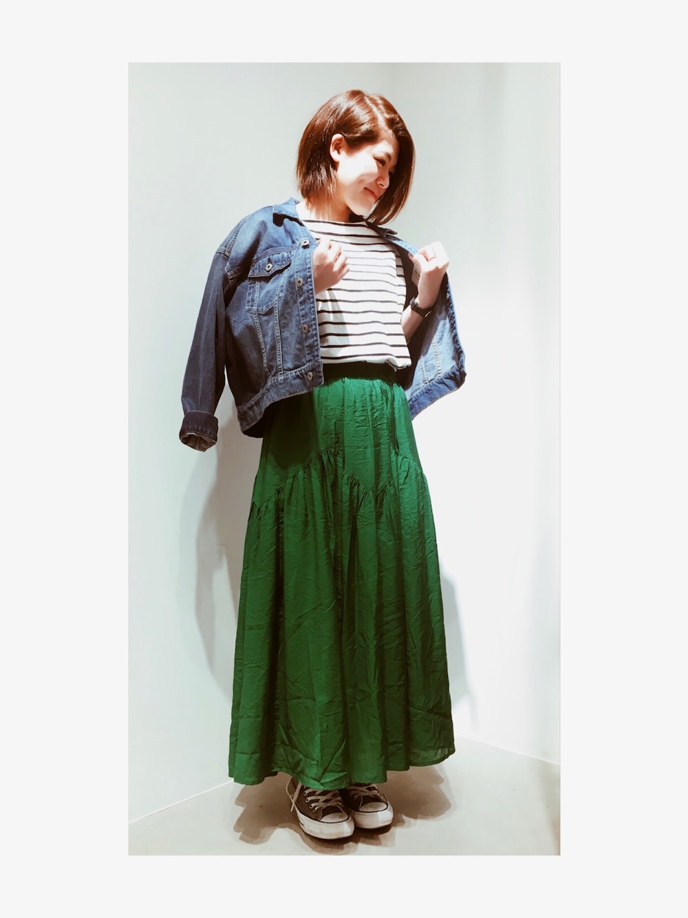 グリーン系のスカート、ホワイト系のTシャツ/カットソー、ブルー系のデニムジャケットを着用したレディースの冬コーディネートの1枚目の写真