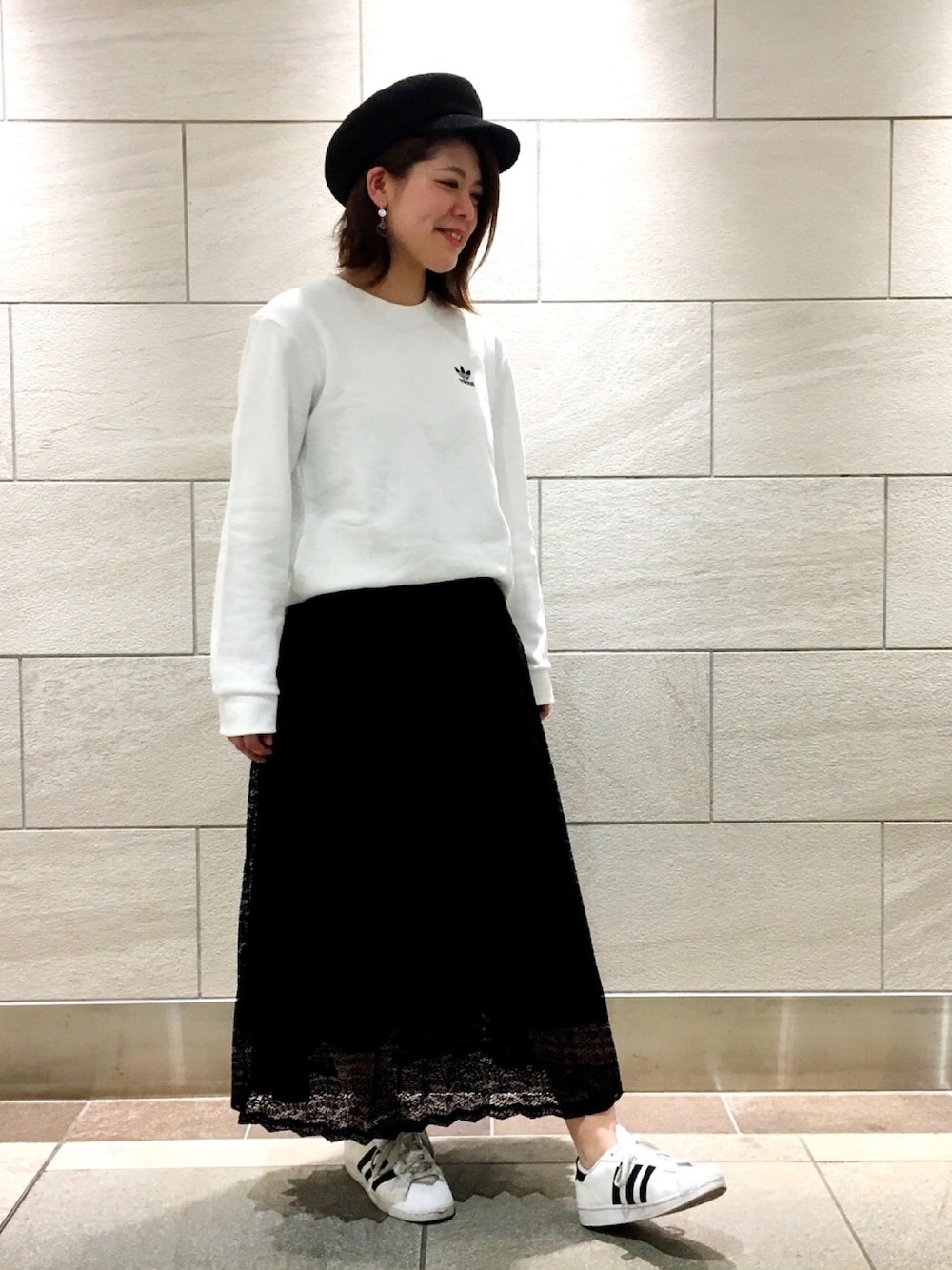 ホワイト系のスウェット、ブラック系のスカート、ホワイト系のスニーカーを着用したレディースの春コーディネートの1枚目の写真