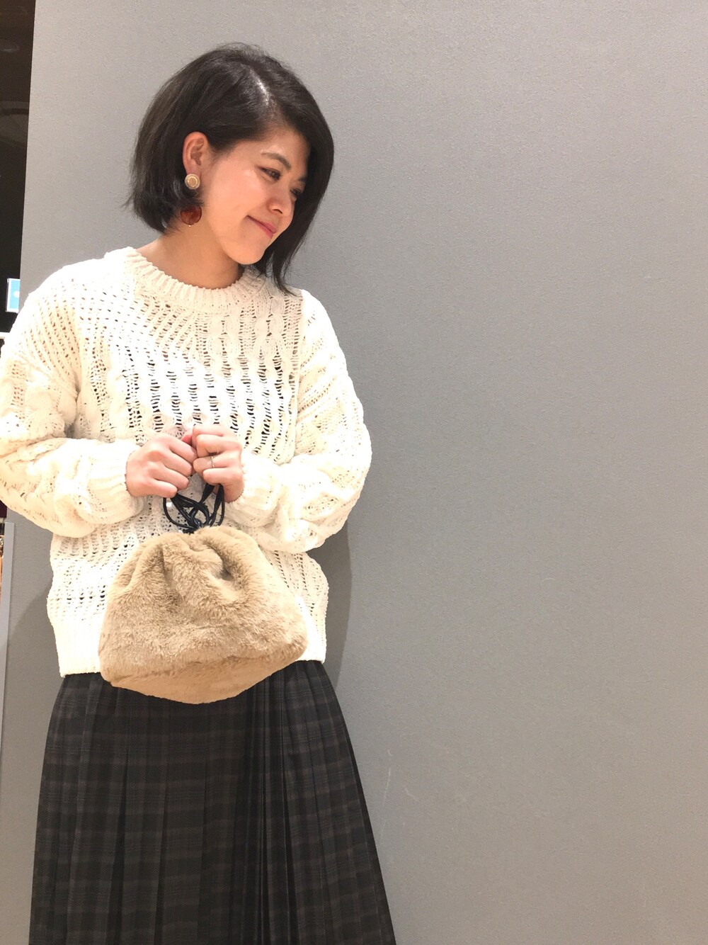 ホワイト系のニット/セーター、ベージュ系のハンドバッグ、グリーン系のスカートを着用したレディースの秋コーディネートの1枚目の写真