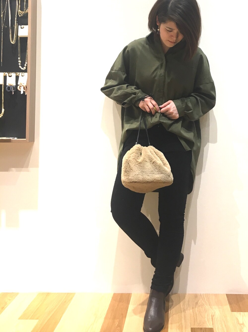 グリーン系のチュニック、ブラック系のその他パンツ、ベージュ系のハンドバッグを着用したレディースの冬コーディネートの1枚目の写真