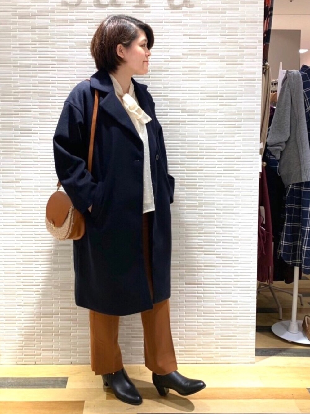 イエロー系のショルダーバッグ、ブラック系のブーツ、ブラウン系のその他パンツを着用したレディースの秋コーディネートの1枚目の写真