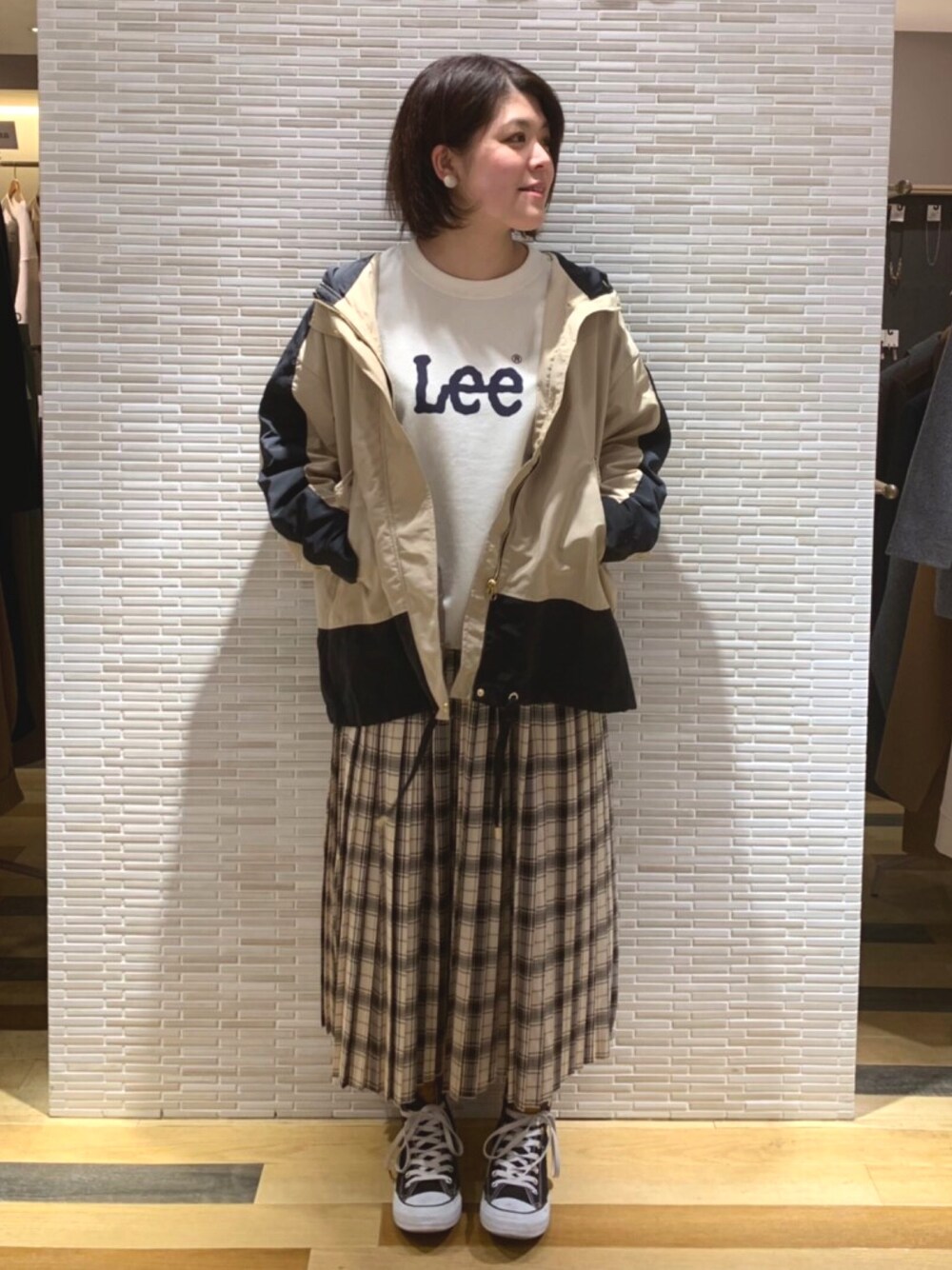 ホワイト系のスウェット、ベージュ系のスカート、ブラック系のスニーカーを着用したレディースの春コーディネートの1枚目の写真