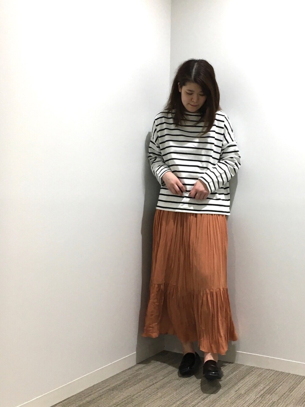 ホワイト系のTシャツ/カットソー、オレンジ系のスカート、ブラック系のローファーを着用したレディースの春コーディネートの1枚目の写真