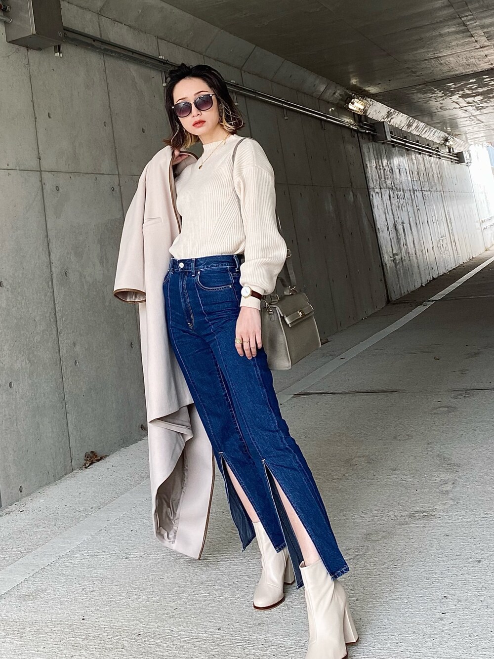 ホワイト系のニット/セーター、ブルー系のデニムパンツ、グレー系のハンドバッグを着用したレディースの冬コーディネートの1枚目の写真