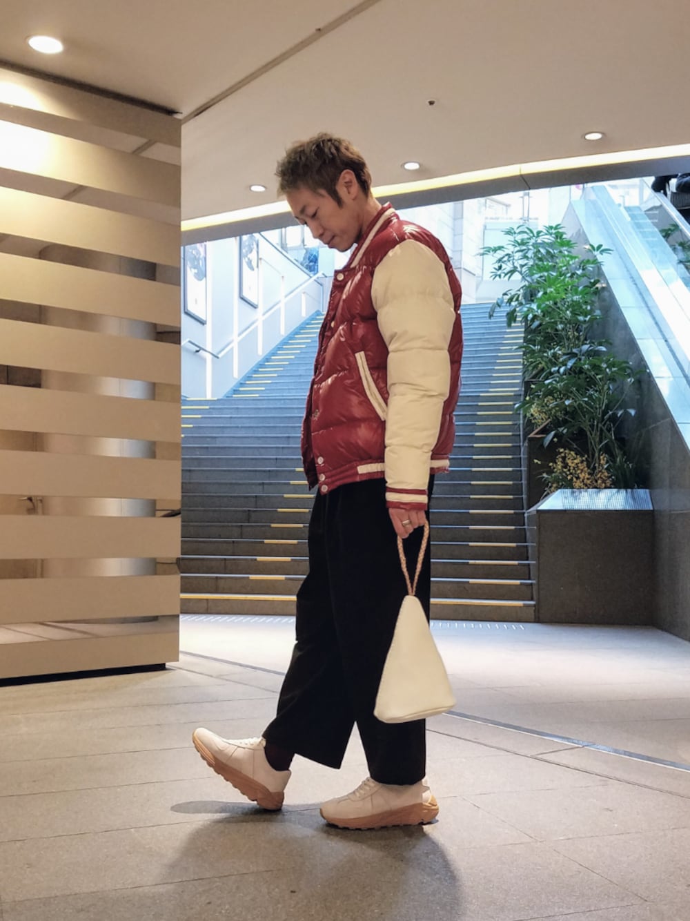 ホワイト系のスニーカー、ホワイト系のバッグ、レッド系のダウンジャケット/コートを着用したメンズの冬コーディネートの1枚目の写真