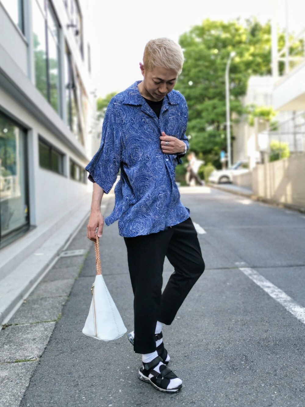 ホワイト系のハンドバッグ、ブラック系のサンダルを着用したメンズの春コーディネートの1枚目の写真