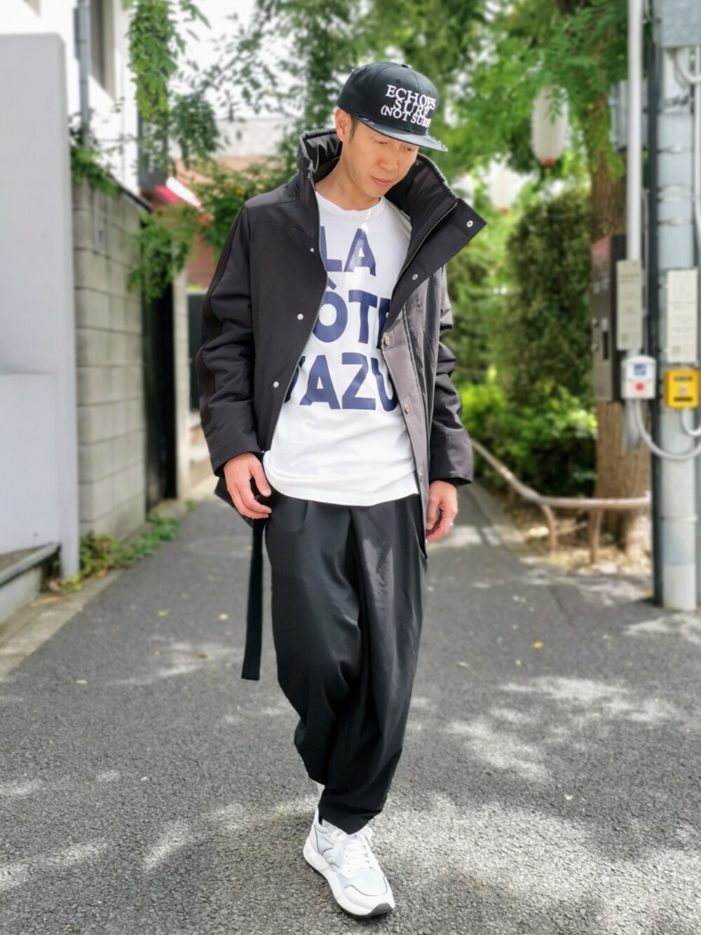 ホワイト系のステンカラーコート、ブラック系のキャップを着用したメンズの秋コーディネートの1枚目の写真