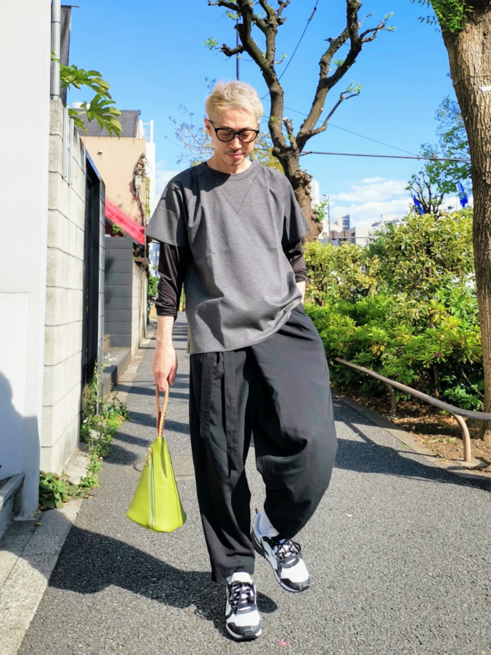 ブラック系のスニーカー、グレー系のTシャツ/カットソー、グリーン系のハンドバッグを着用したメンズの春コーディネートの1枚目の写真