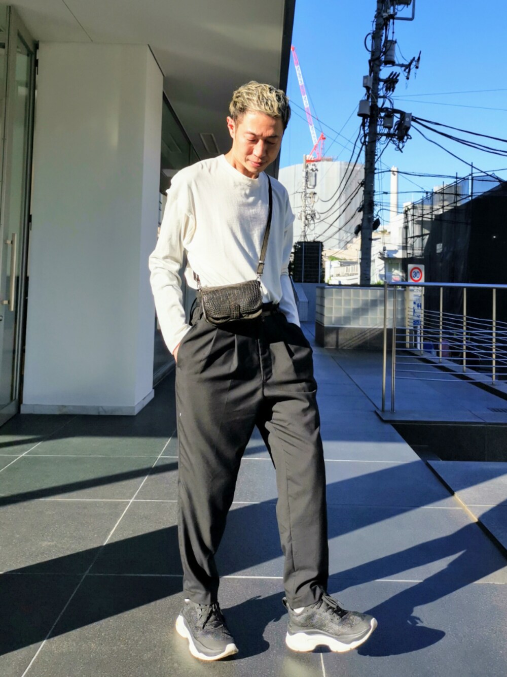 ブラック系のショルダーバッグ、ブラック系のスニーカー、ホワイト系のTシャツ/カットソーを着用したメンズの夏コーディネートの1枚目の写真