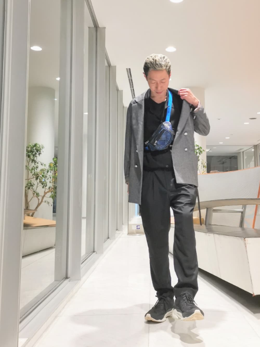 ブルー系のボディバッグ/ウエストポーチ、グレー系のテーラードジャケット、ブラック系のスニーカーを着用したメンズの秋コーディネートの1枚目の写真