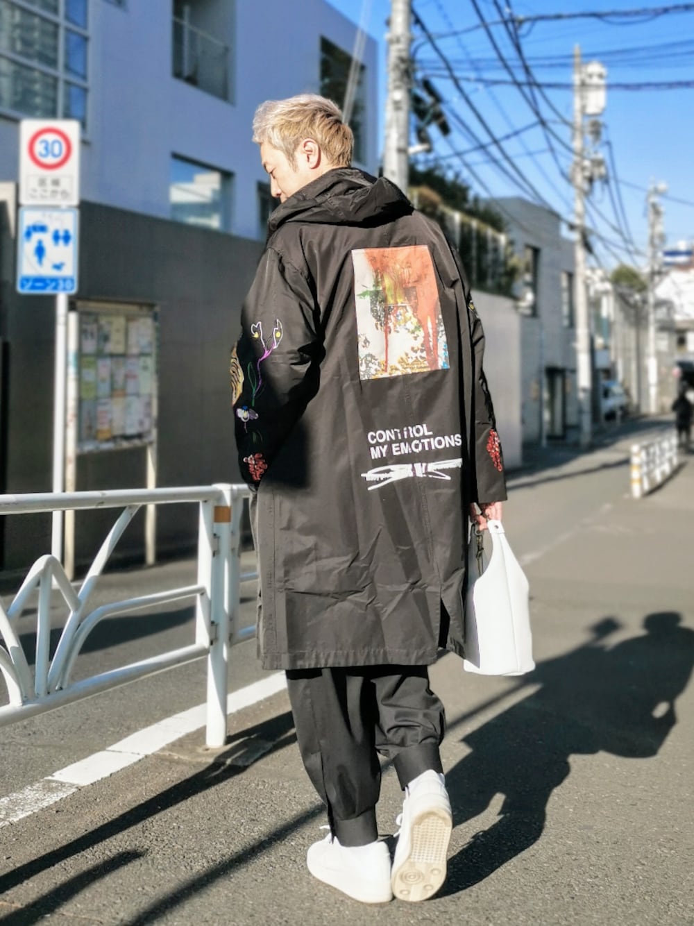 ブラック系のジャケット/アウター、ホワイト系のTシャツ/カットソー、ホワイト系のハンドバッグを着用したメンズの冬コーディネートの1枚目の写真