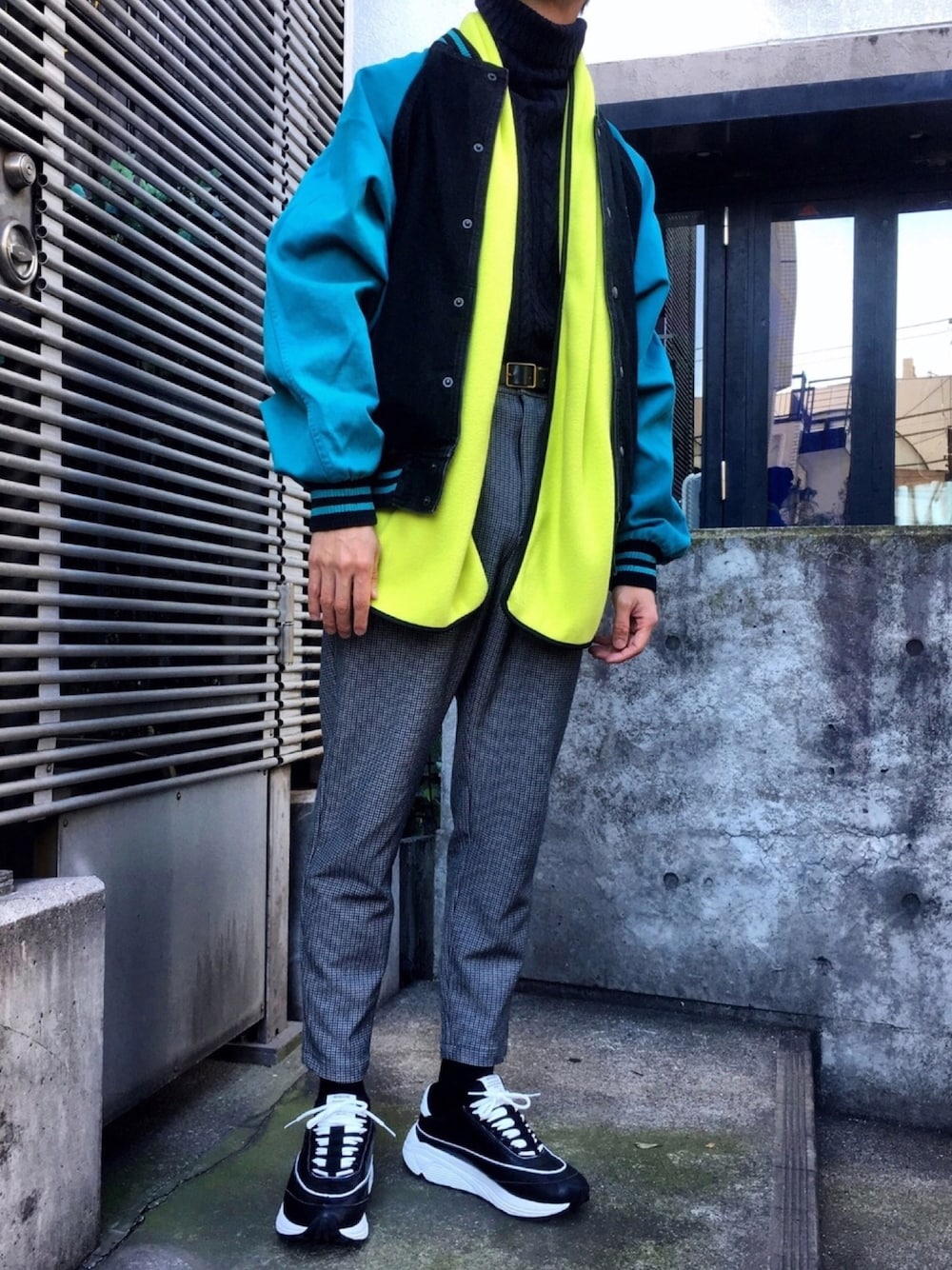 ブラック系のニット/セーター、グレー系のスラックス、イエロー系のマフラーを着用したメンズの冬コーディネートの1枚目の写真