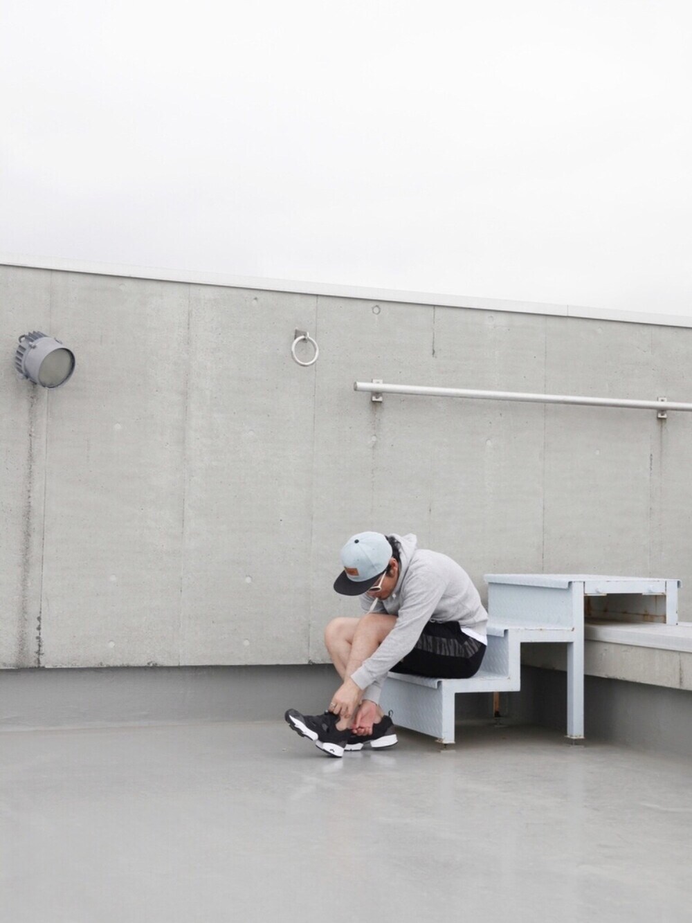 ブラック系のスニーカー、ブルー系のセットアップ、グレー系のパーカーを着用したメンズの春コーディネートの1枚目の写真