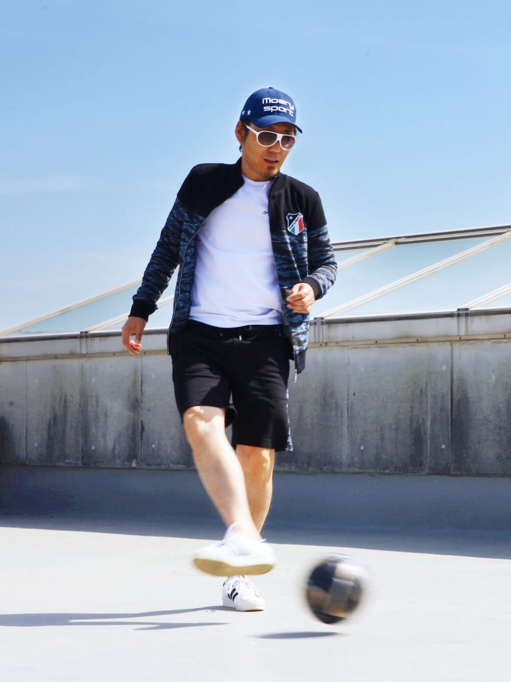 ブルー系のセットアップ、ブラック系のスニーカー、ホワイト系のサングラスを着用したメンズの春コーディネートの1枚目の写真