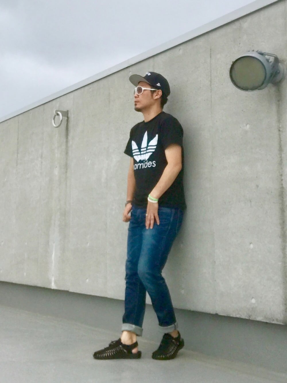 ブラック系のサンダル、ブルー系のデニムパンツ、ブラック系のTシャツ/カットソーを着用したメンズの夏コーディネートの1枚目の写真
