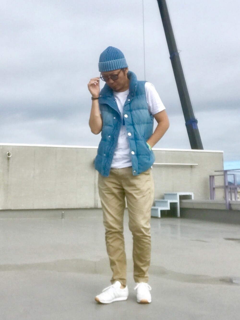 ホワイト系のTシャツ/カットソー、ブルー系のベスト、ベージュ系のチノパンツを着用したメンズの秋コーディネートの1枚目の写真