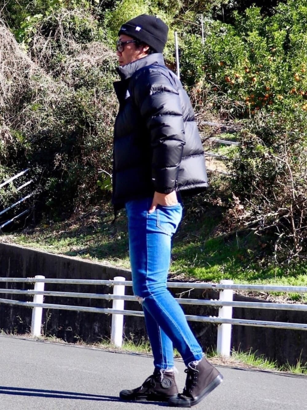 ブラック系のダウンジャケット/コート、ブルー系のデニムパンツ、ブラック系のスニーカーを着用したメンズの冬コーディネートの1枚目の写真