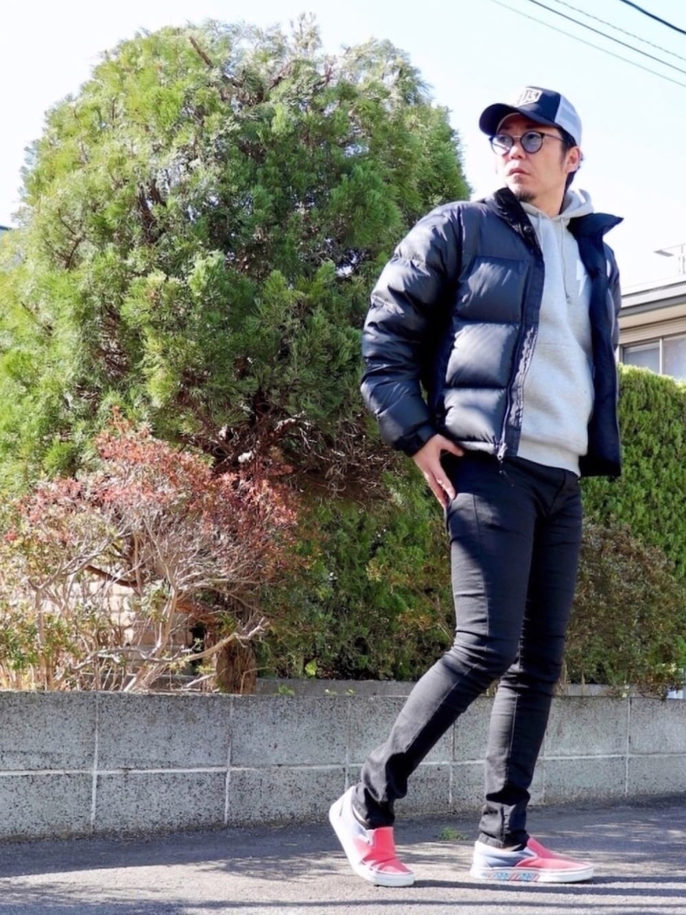 ブラック系のデニムパンツ、ブラック系のダウンジャケット/コート、レッド系のスニーカーを着用したメンズの冬コーディネートの1枚目の写真