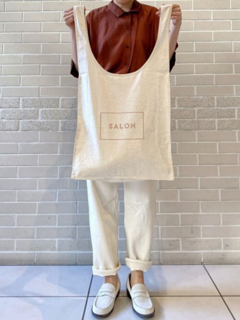 ベージュ系のハンドバッグ、ホワイト系のローファー、ホワイト系のデニムパンツを着用したレディースの夏コーディネートの1枚目の写真