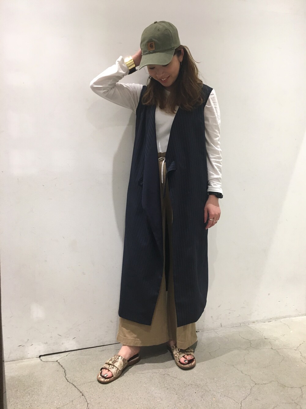 ベージュ系のその他パンツ、ブラック系のバングル/リストバンド、グリーン系のキャップを着用したレディースの春コーディネートの1枚目の写真