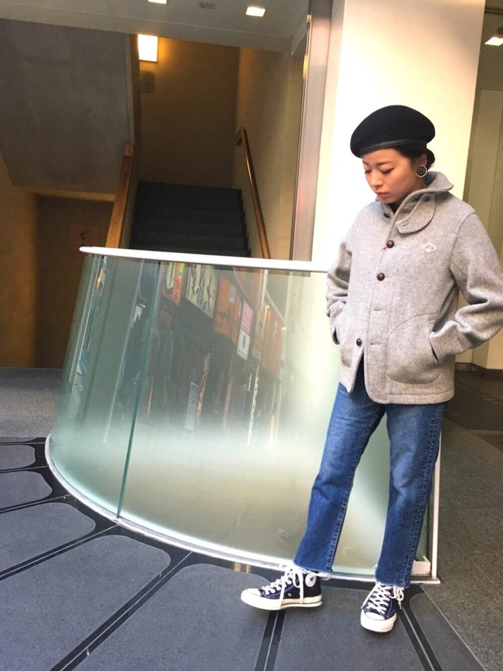 ブルー系のデニムパンツ、グレー系のステンカラーコート、ブラック系のハンチング/ベレー帽を着用したレディースの冬コーディネートの1枚目の写真