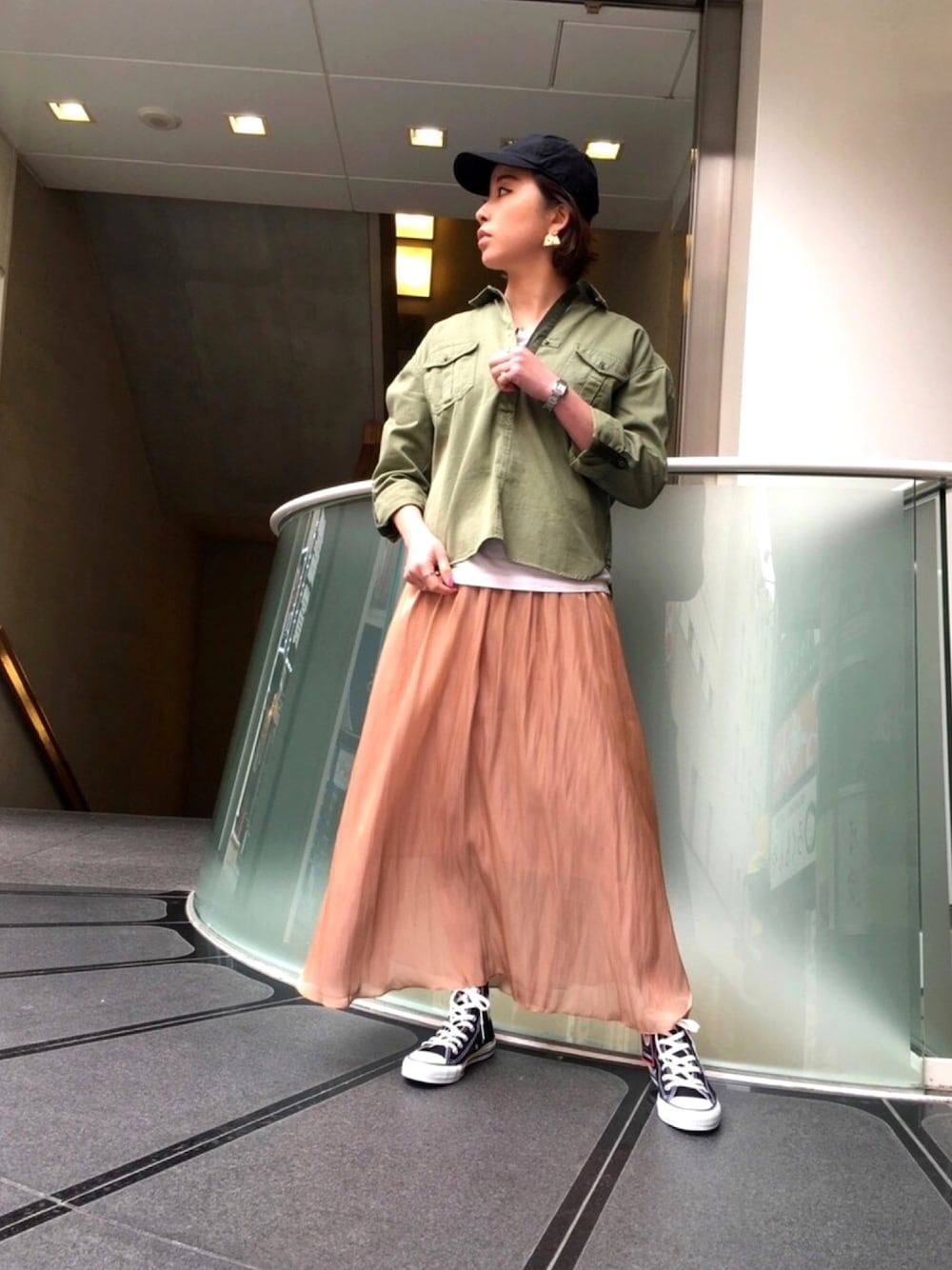 ベージュ系のスカート、グリーン系のシャツ/ブラウス、ブラック系のシューズを着用したレディースの春コーディネートの1枚目の写真