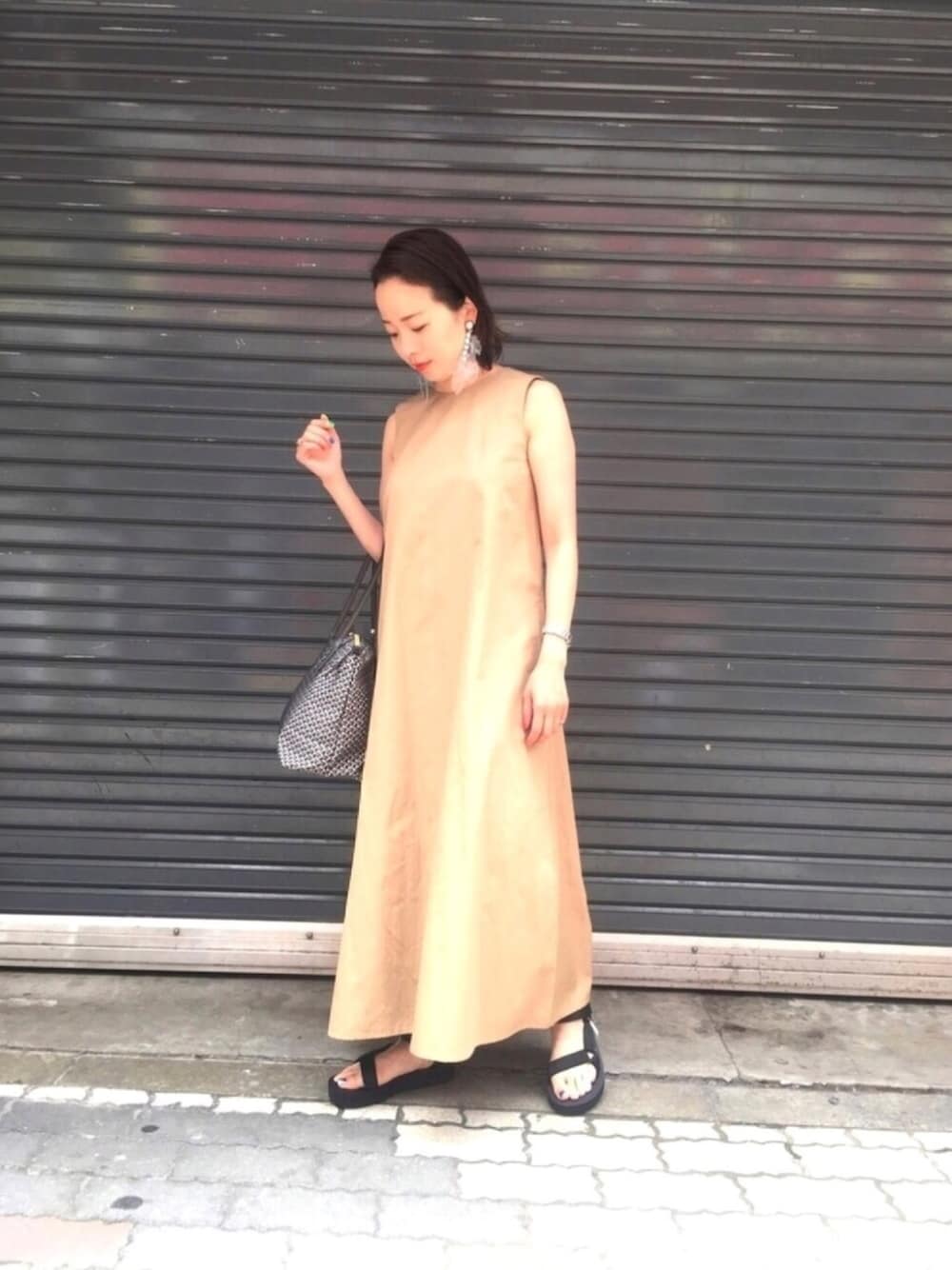 ベージュ系のワンピース、ブラック系のサンダル、グレー系のトートバッグを着用したレディースの夏コーディネートの1枚目の写真